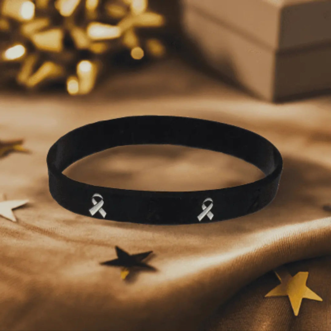 Black wristband with a white ribbon symbol on a textured surface with decorative elements.