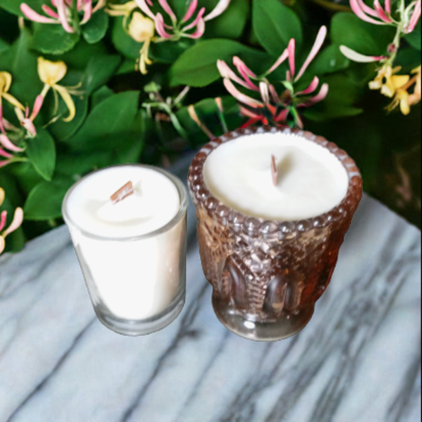 Two candles in decorative holders with a floral background