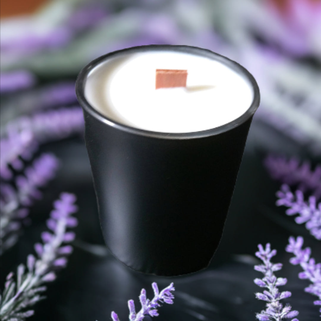 Black candle in a white container with a blurred lavender background
