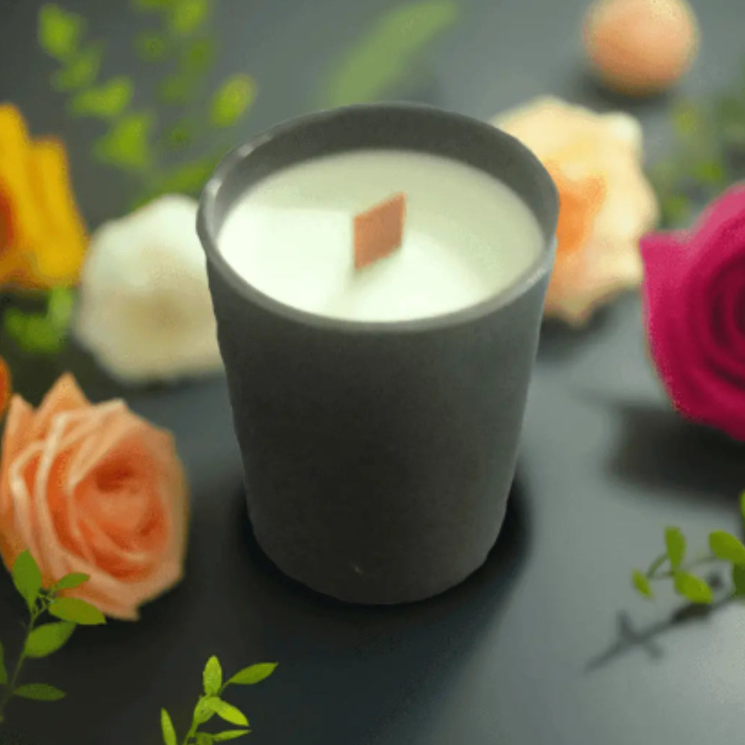 Candle in a black holder with flowers on a dark surface