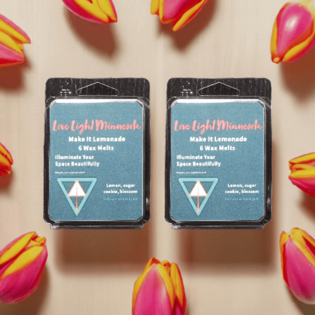Two packages of Live Light Minnesota wax melts surrounded by tulips on a beige background