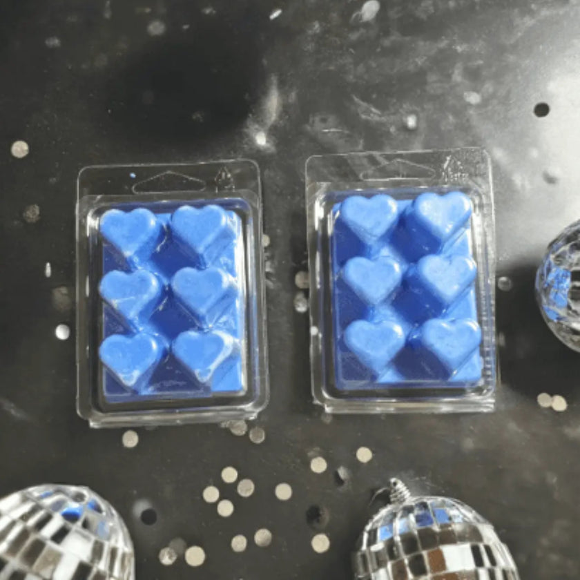 Two packages of blue heart-shaped items on a reflective surface with disco balls.