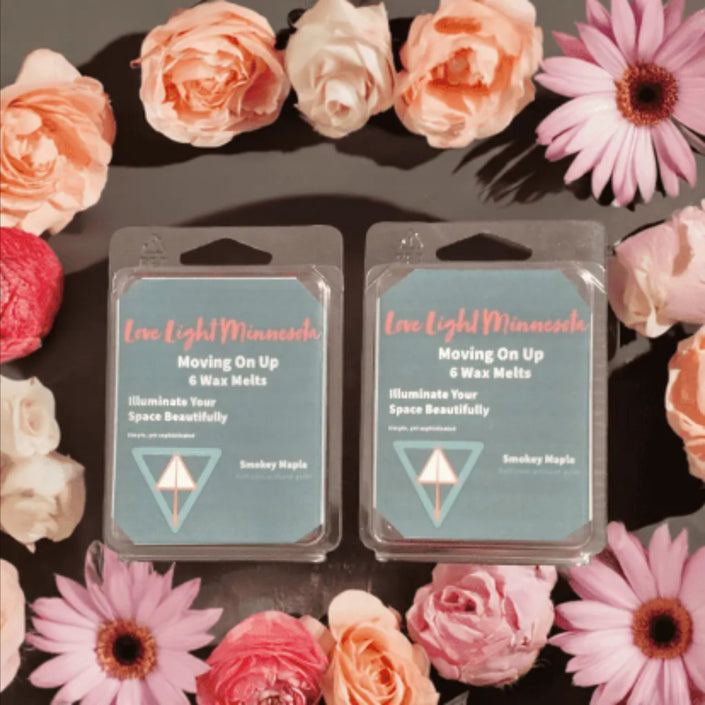 Two wax melt packages with floral arrangement on a dark background