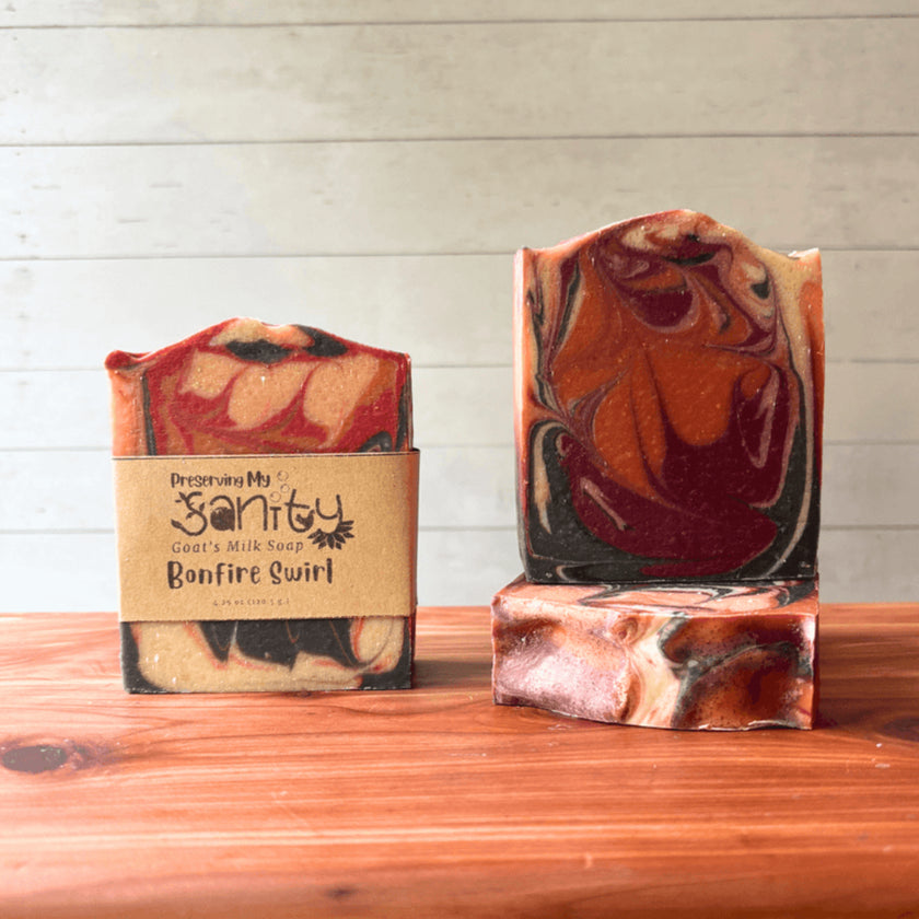 Two bars of soap called Bonfire Swirl with a marbled design on a wooden surface, one with a visible label.