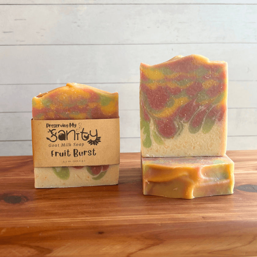 Three bars of colorful soap called Fruit Burst with a 'Preserving My Sanity' box on a wooden surface.