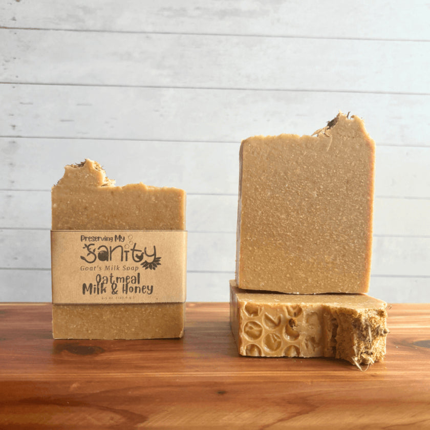 Two bars of soap with a label saying Oatmeal milk & honey on a wooden surface and a light gray background