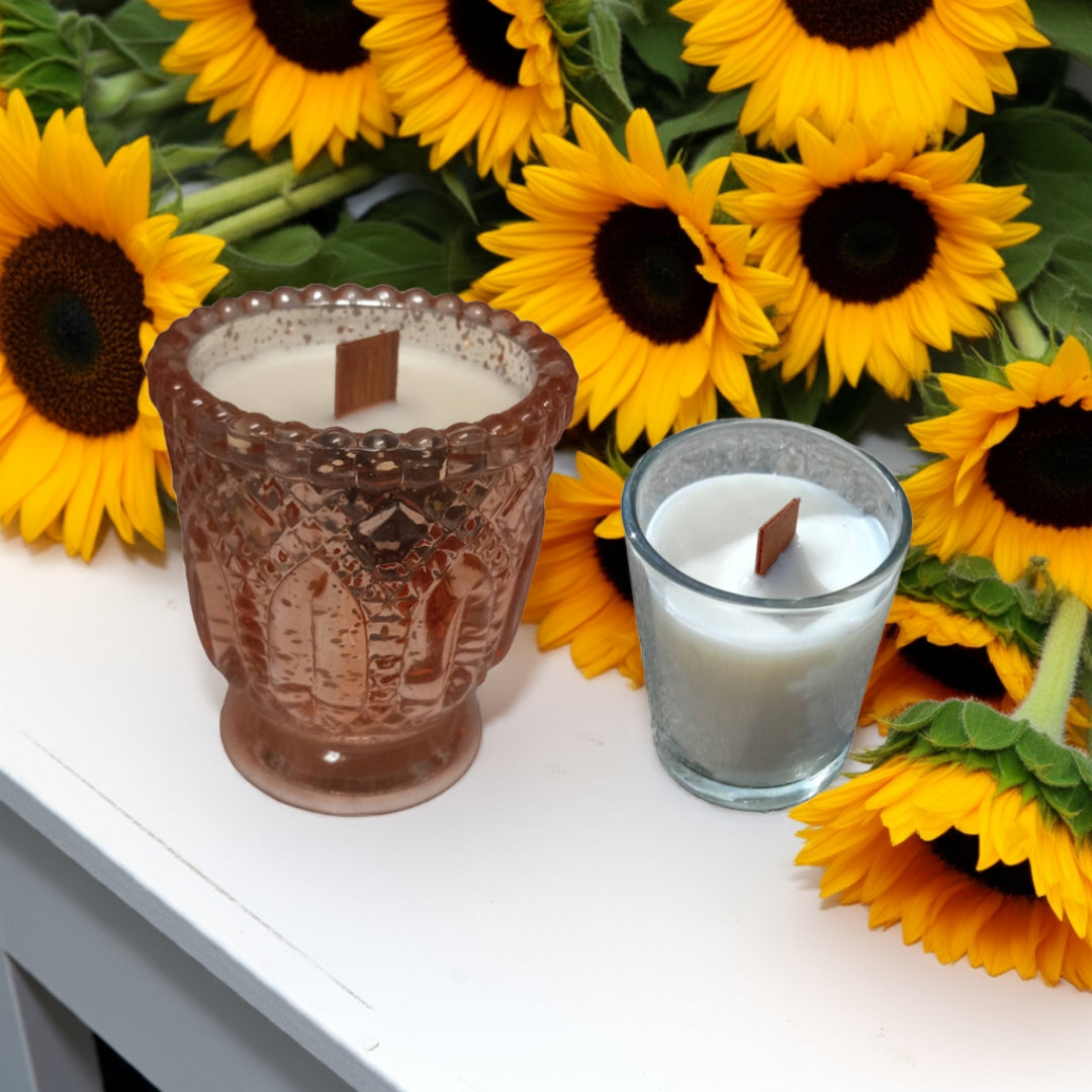 Two candles in decorative holders with sunflowers in the background